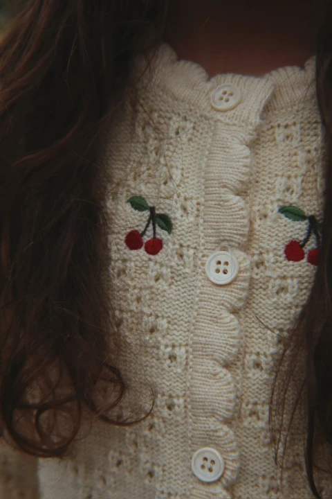 Konges Sløjd Cocolo Cardigan Buttercream – detal dzianiny, guzików i czerwonych haftów wisienek