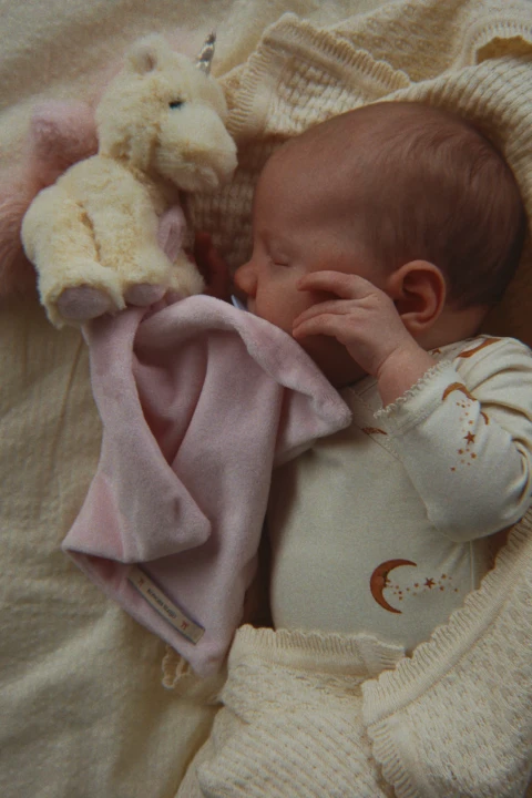 Konges Sløjd Basic LS Newborn Body Moon na niemowlęciu z różowym materiałem
