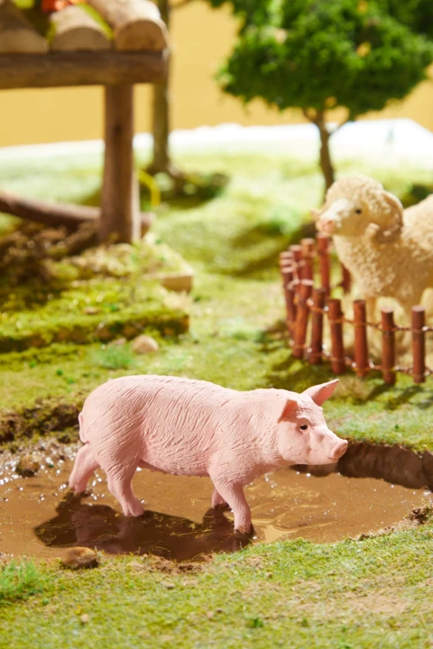 Figurka świni Mideer przy zagrodzie w realistycznej scenerii farmy