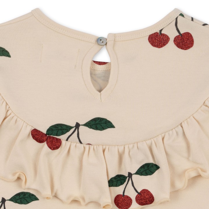 Zbliżenie nadruku wiśni z subtelnym efektem glitter w sukience Konges Sløjd.