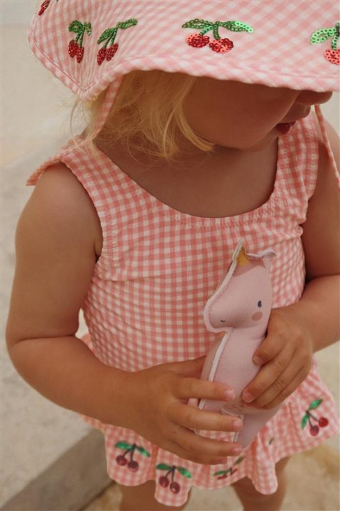 Różowy strój kąpielowy dziecięcy Konges Sløjd pokazany w stylizacji.