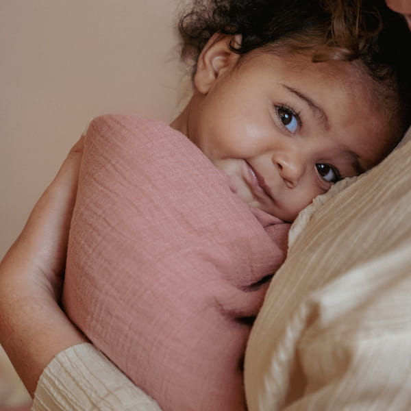 Otulacz muślinowy pudrowy róż przy dziecku