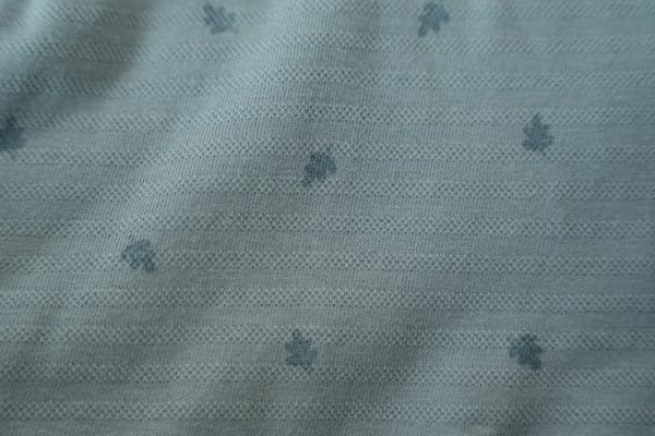 Zbliżenie tkaniny otulacza muślinowego niebieskiego w delikatne listki