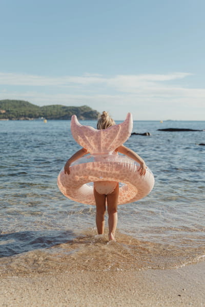 Koło do pływania Dreamy Mermaid przy dziecku na plaży