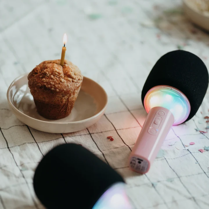 Różowy mikrofon karaoke KIDYMIC z kolorowym podświetleniem LED obok babeczki