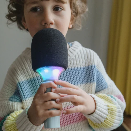 Dziecko trzyma zielony mikrofon karaoke KIDYMIC z kolorowym podświetleniem LED