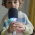 Dziecko trzyma zielony mikrofon karaoke KIDYMIC z kolorowym podświetleniem LED