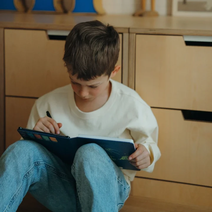 Dziecko korzysta z granatowego tabletu LCD KIDYDRAW MINI Galaxy podczas zabawy w domu