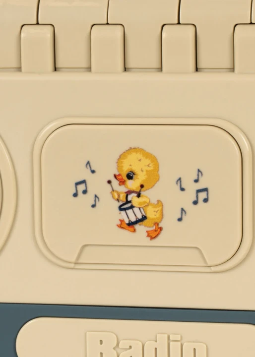 Radio-zabawka Baby Boombox – zbliżenie na przycisk z ptaszkiem i nutkami
