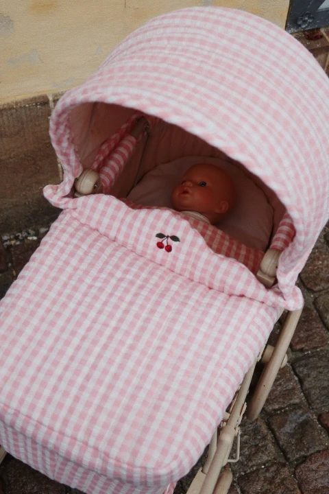Konges Sløjd Elli The Doll lalka pod różowym pikowanym okryciem