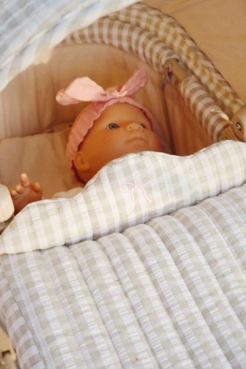 Konges Sløjd Elli The Doll lalka ułożona w wiklinowym koszu