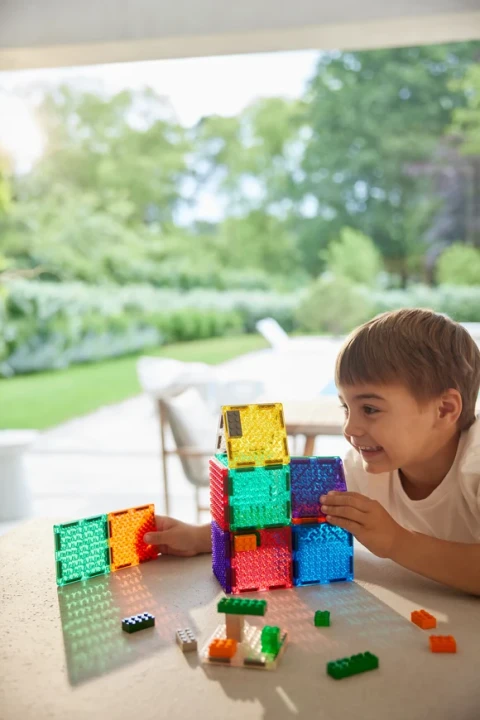Cleverclixx Brick Tiles Pack Intense 16 elementów, chłopiec budujący przy stole